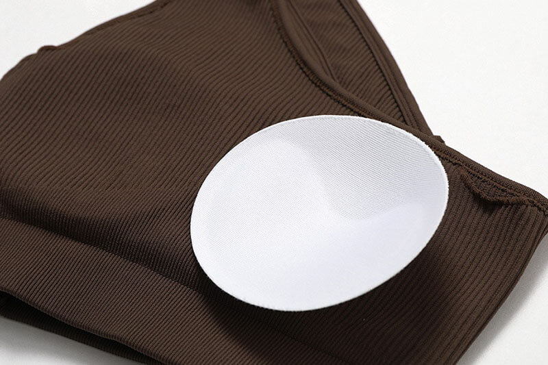 Close-up of brown women's one-shoulder sports bra with breathable nylon fabric and removable pads for fitness and comfort.